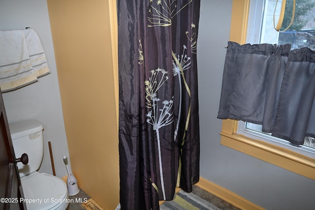 full bathroom featuring a shower with shower curtain, baseboards, a healthy amount of sunlight, and toilet