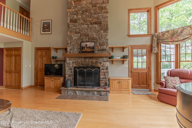 72 Adams Dr, Waymart, PA 18472 - living room featuring light wood-style floors, a towering ceiling, a stone fireplace, and healthy amount of natural light