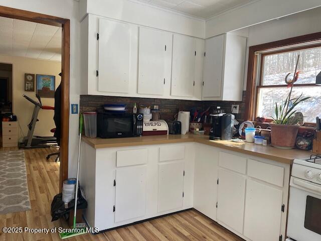 kitchen with white cabinets, light wood-type flooring, and white range with gas cooktop