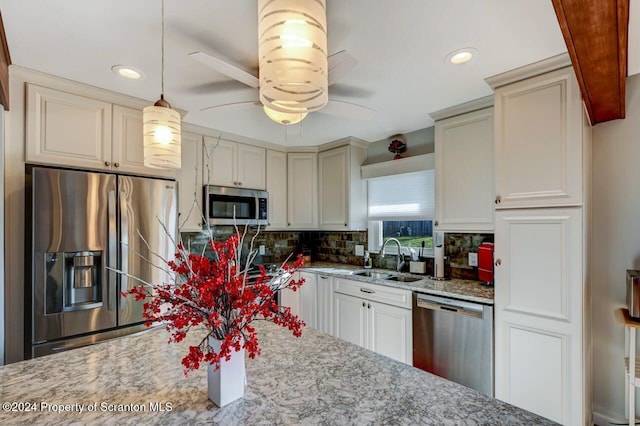 kitchen featuring backsplash, light stone countertops, sink, and appliances with stainless steel finishes