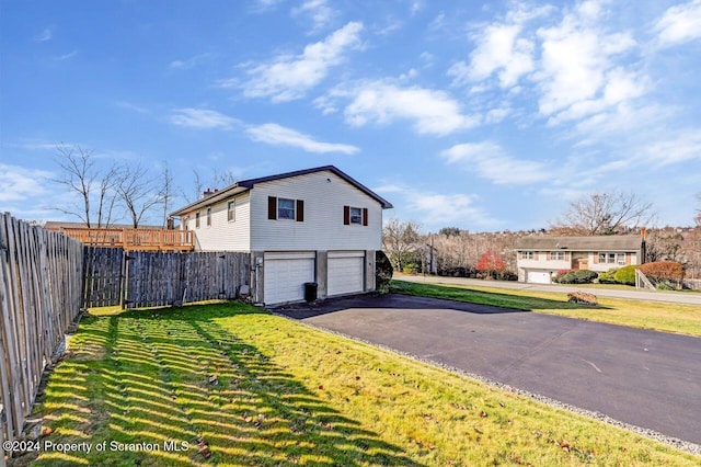 view of side of property featuring a garage and a lawn