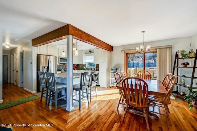 dining space with light hardwood / wood-style floors, sink, and a chandelier