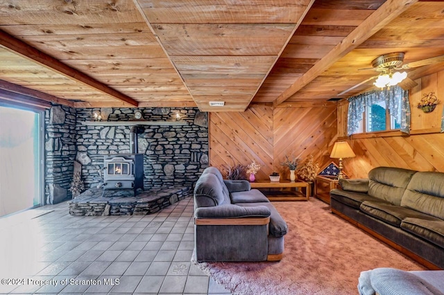 living room with wood ceiling, plenty of natural light, a wood stove, and wooden walls