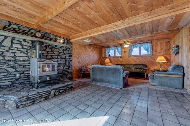 unfurnished living room featuring wood ceiling, wooden walls, beam ceiling, tile patterned flooring, and a wood stove