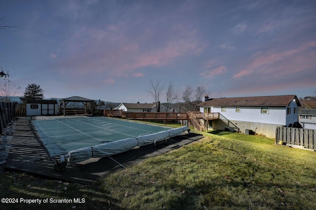 view of tennis court featuring a gazebo, a shed, a yard, and a covered pool