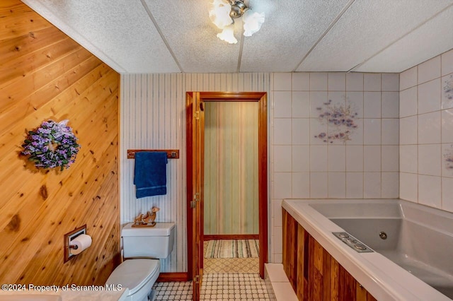 bathroom with toilet, a drop ceiling, and a tub