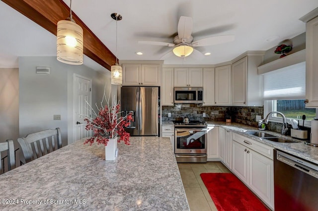 kitchen featuring ceiling fan, sink, hanging light fixtures, tasteful backsplash, and appliances with stainless steel finishes