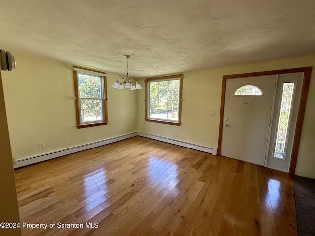 entryway featuring an inviting chandelier, a baseboard radiator, light hardwood / wood-style flooring, and a healthy amount of sunlight