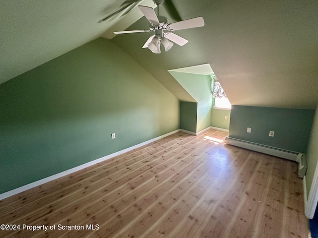 additional living space with light wood-type flooring, vaulted ceiling, ceiling fan, and a baseboard heating unit