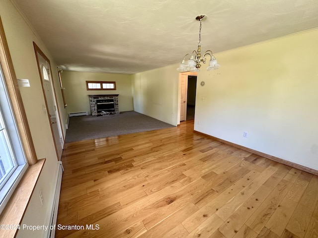 unfurnished living room featuring a fireplace, light hardwood / wood-style flooring, an inviting chandelier, and plenty of natural light