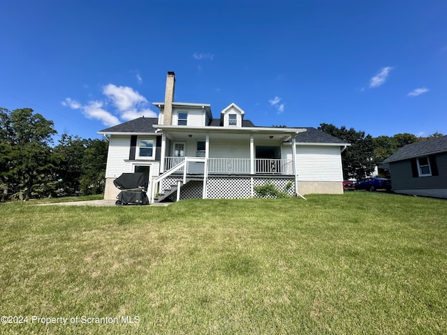 rear view of property featuring covered porch and a yard