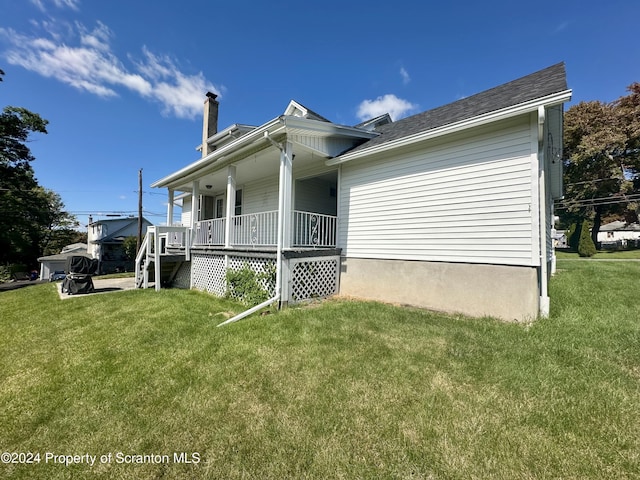 view of side of property with a porch and a lawn