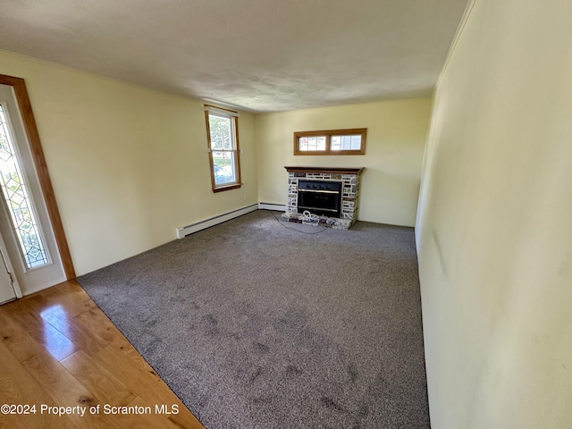 unfurnished living room featuring baseboard heating, a stone fireplace, and hardwood / wood-style flooring