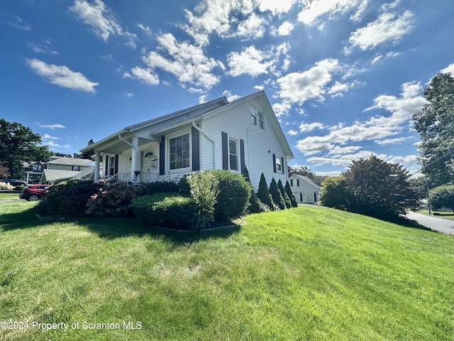 view of home's exterior with covered porch and a yard