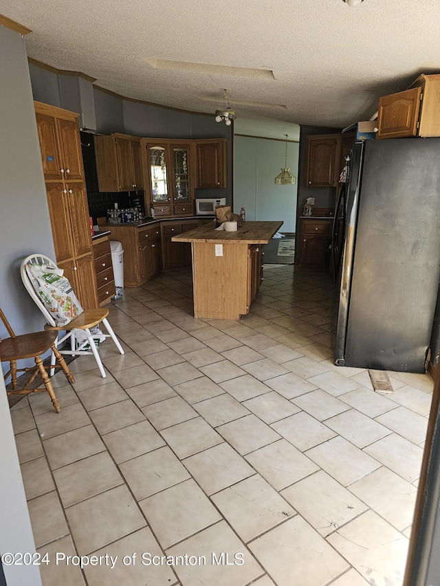 kitchen featuring a kitchen island, black fridge, a kitchen bar, and a textured ceiling