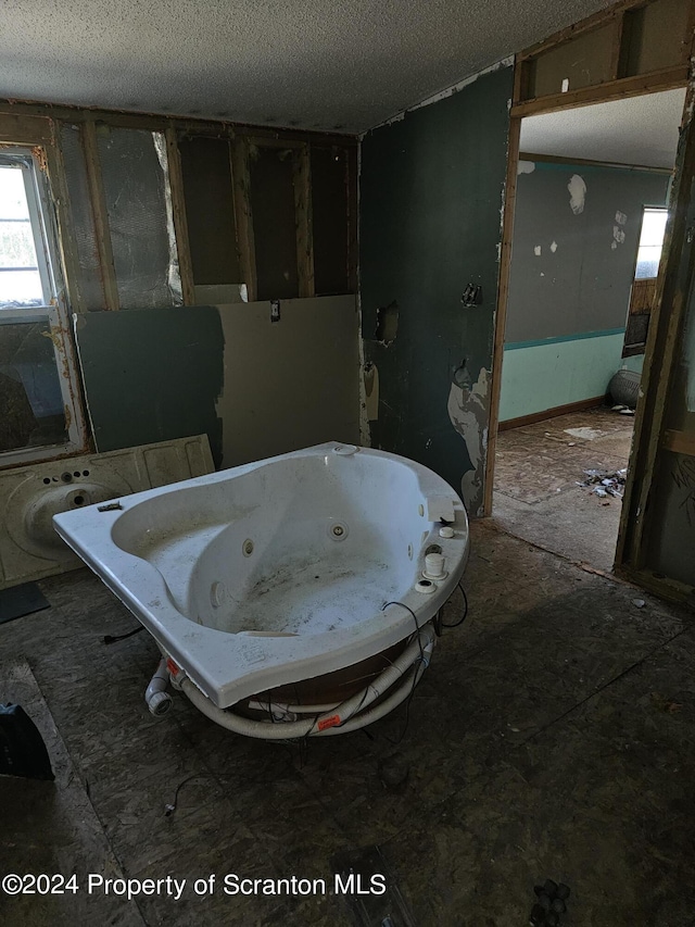 bathroom featuring a textured ceiling and a tub