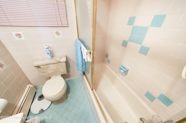 bathroom featuring baseboard heating, bath / shower combo with glass door, tile walls, and toilet