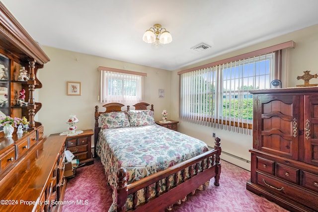 carpeted bedroom featuring baseboard heating, multiple windows, and an inviting chandelier