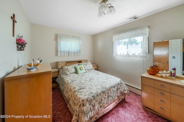 bedroom with dark colored carpet and baseboard heating