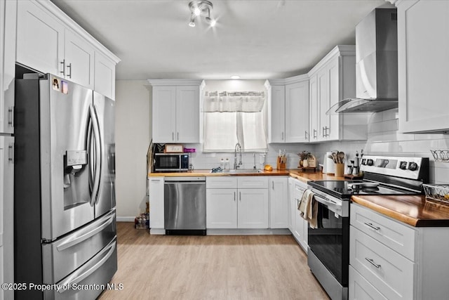 kitchen featuring white cabinetry, wall chimney exhaust hood, and appliances with stainless steel finishes