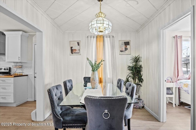 dining area with crown molding, a chandelier, and light hardwood / wood-style floors