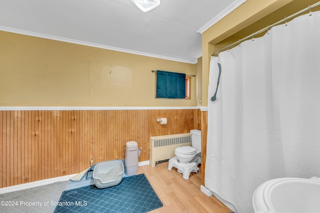 bathroom featuring radiator, wooden walls, crown molding, hardwood / wood-style flooring, and toilet