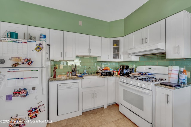 kitchen with light stone countertops, white appliances, white cabinetry, and sink