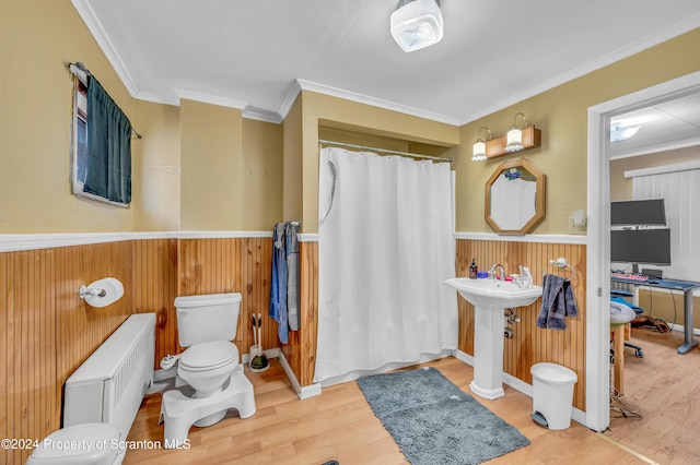 bathroom with radiator, crown molding, toilet, wooden walls, and hardwood / wood-style flooring