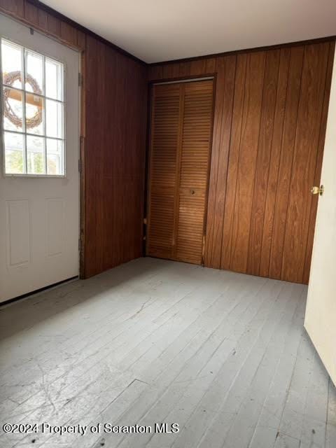 unfurnished bedroom with wood walls, light hardwood / wood-style flooring, and a closet