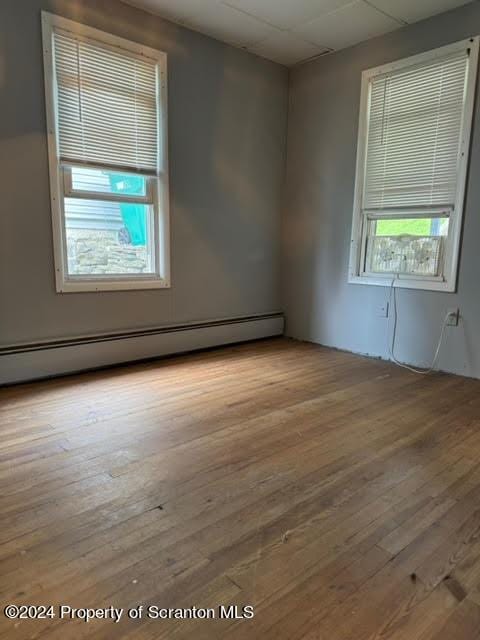 unfurnished room with baseboard heating and light hardwood / wood-style flooring