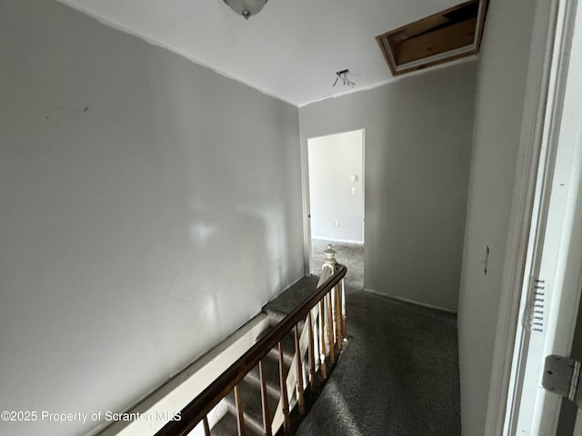 corridor with attic access, an upstairs landing, and dark colored carpet