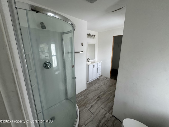 bathroom with toilet, a stall shower, and vanity