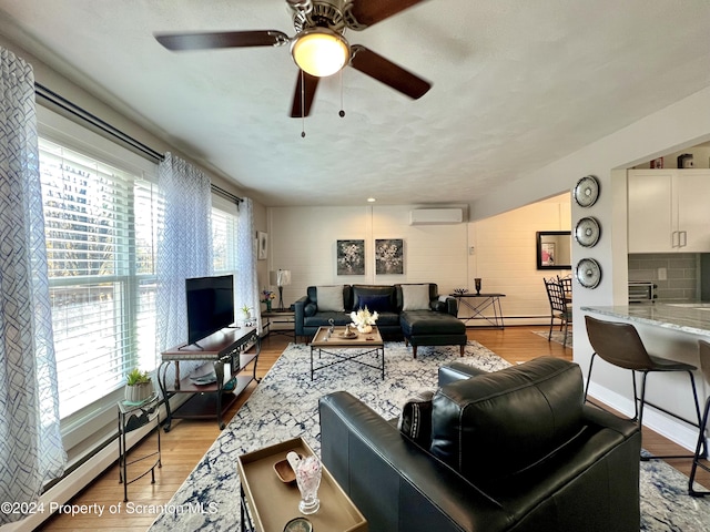 living room featuring a wall mounted AC, a wealth of natural light, a baseboard heating unit, and light wood-type flooring