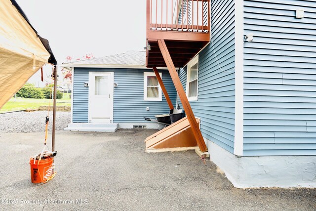 property entrance featuring a shingled roof and a balcony