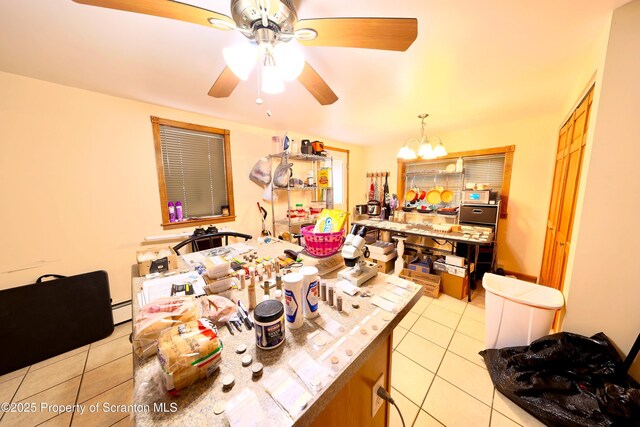 kitchen featuring light tile patterned floors, light countertops, baseboard heating, and ceiling fan with notable chandelier