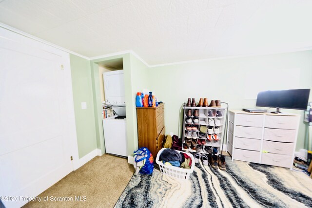 bedroom featuring carpet floors, crown molding, stacked washing maching and dryer, and baseboards