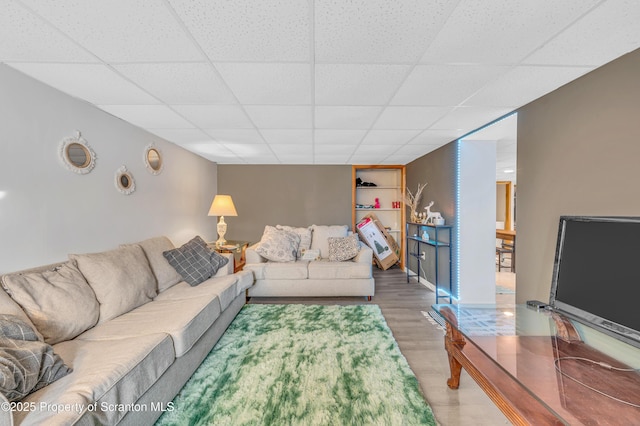 living room featuring hardwood / wood-style flooring, a paneled ceiling, and built in shelves