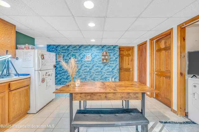 kitchen with washer / clothes dryer, a drop ceiling, white fridge, and light tile patterned floors