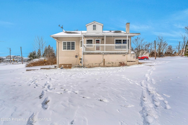 snow covered rear of property with a porch