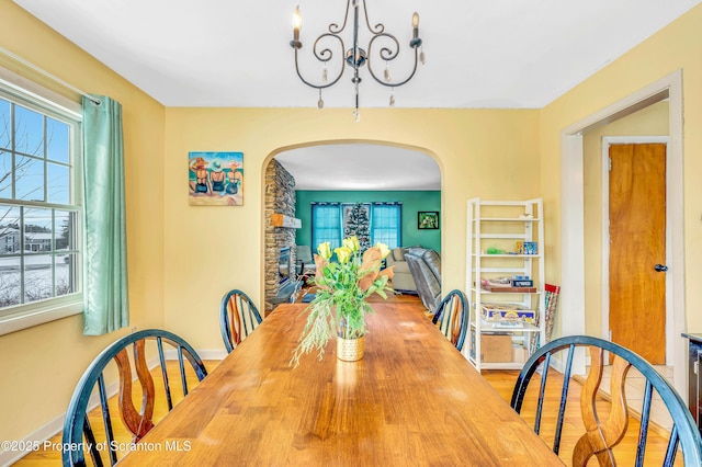 dining room with wood-type flooring, a fireplace, and a chandelier