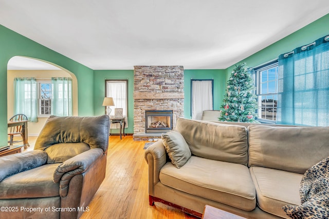 living room featuring a stone fireplace and light wood-type flooring