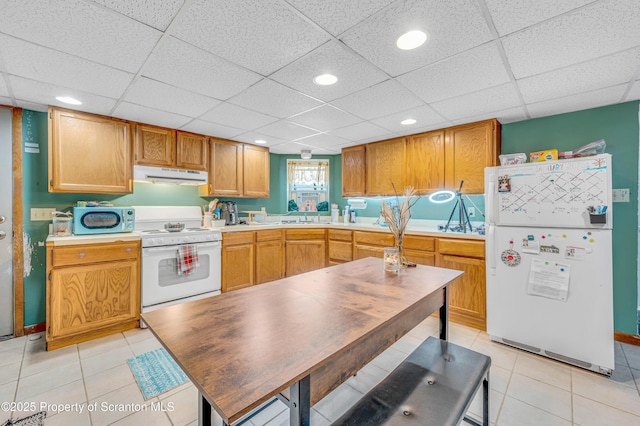 kitchen featuring a paneled ceiling, light tile patterned floors, and white appliances