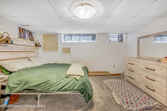 carpeted bedroom featuring multiple windows, a baseboard heating unit, and a drop ceiling