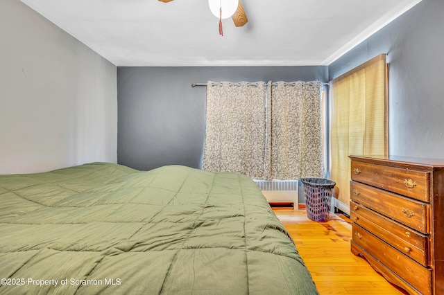 bedroom featuring ceiling fan, radiator, and light wood-type flooring