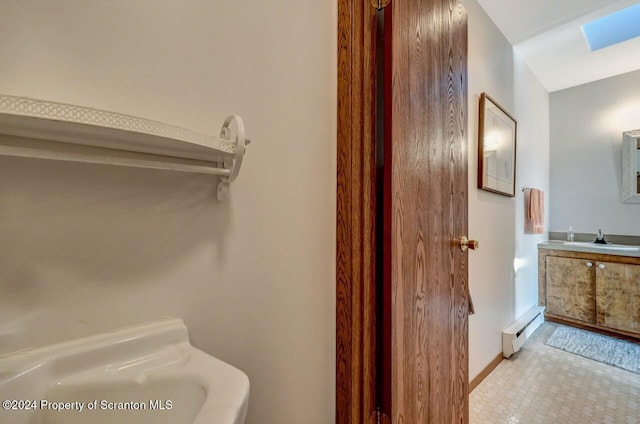 bathroom with a skylight, a baseboard heating unit, and sink