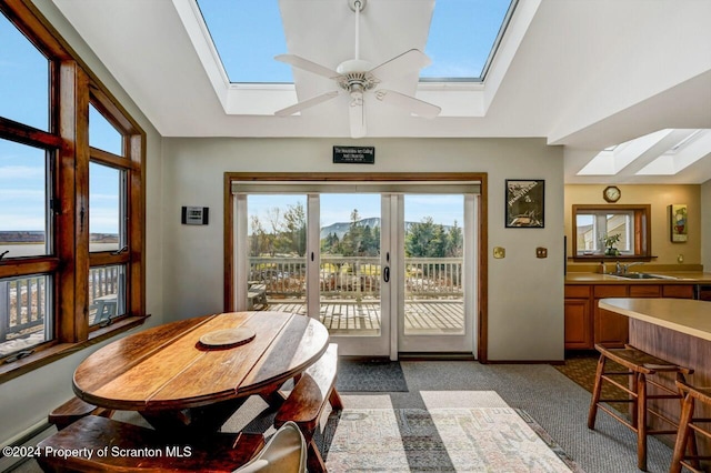 dining space featuring baseboard heating, ceiling fan, sink, and lofted ceiling with skylight