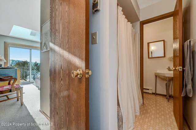 hallway featuring baseboard heating, light carpet, and a skylight