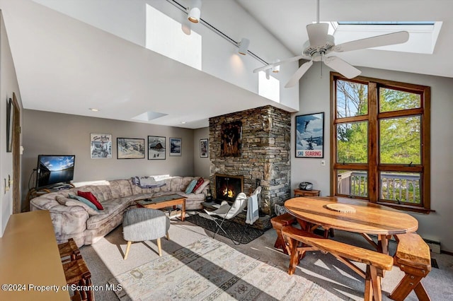 living room with carpet flooring, ceiling fan, a stone fireplace, and lofted ceiling