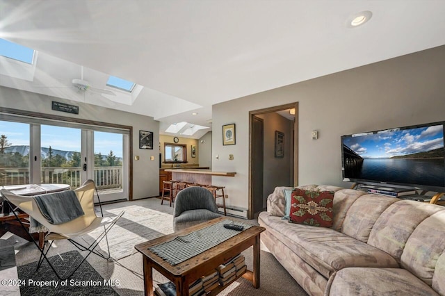 living room with french doors, vaulted ceiling with skylight, ceiling fan, a baseboard radiator, and a mountain view