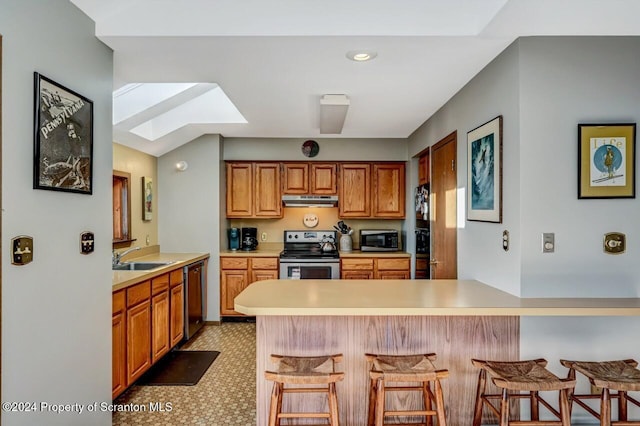 kitchen featuring sink, a breakfast bar area, a skylight, kitchen peninsula, and stainless steel appliances